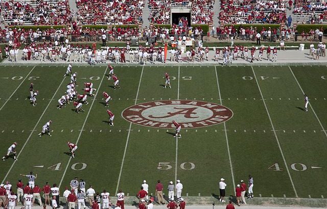 Blick von der Tribüne auf Alabama-Trainingsspiel. Das weiße Team steht an der Line fo Scrimmage, das rote Team in der Verteidigung.