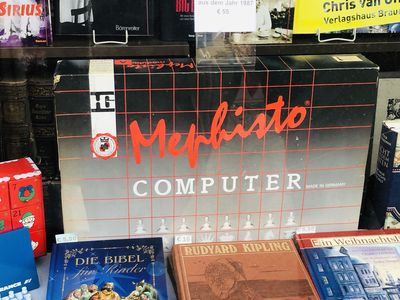 Schwarze Packung eines Mephisto-Schachcomputers in einem Schaufenster. Knapp 40 Jahre alt und dementsprechend abgenutzt. Die Schrift ist rot und weiß.