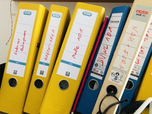Gelbe und blaue Ordnerrücken mit handgeschrieben Beziechnungen wie "Externes Rechnungswesen" oder "Hagen-Orga"