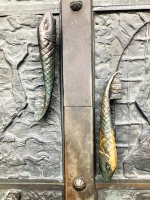 Bronzetür des Doms mit fischförmigen Griffen.