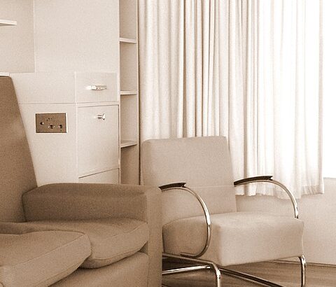 Inneneinrichtung von Huis Sonneveld. Beiger Designerstuhl neben beiger Couch auf beidem Teppich vor beiger Wand.