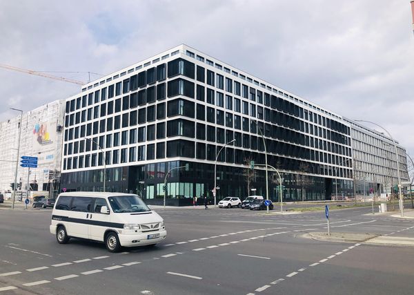 Straßenkreuzung mit weißem VW Bulli und neues Bürogebäude