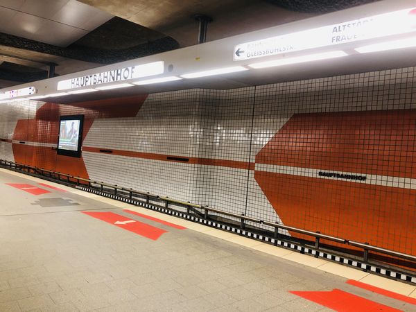 U-Bahn-Station Nürnberg Hauptbahnhof. Eine Wand in orange weiß mit Pfeilmuster, die Anzeige "Hauptbahnhof."