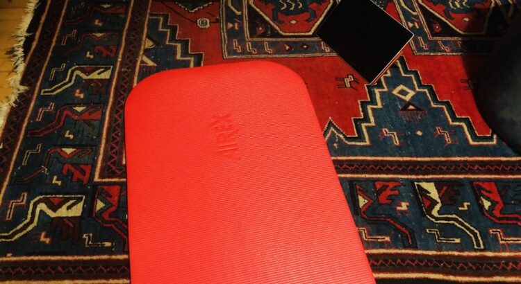 Teppichboden, rote Joga/Sportmatte, Tablet das auf dem Boden steht,