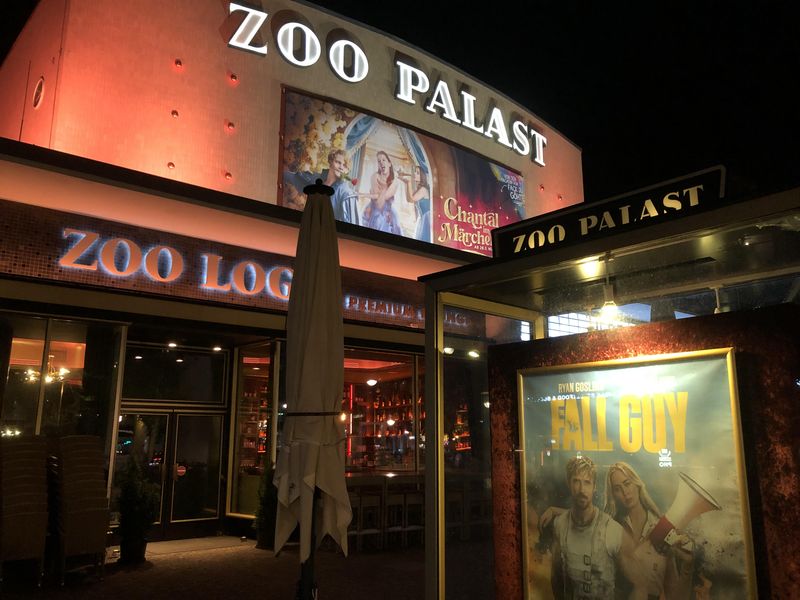 Nacht, Eingangsbereich Zoo Palast mit dessen Fassade, daneben ein Glaskasten mit Fall-Guy-Poster und das Schild der Zoo Loge.