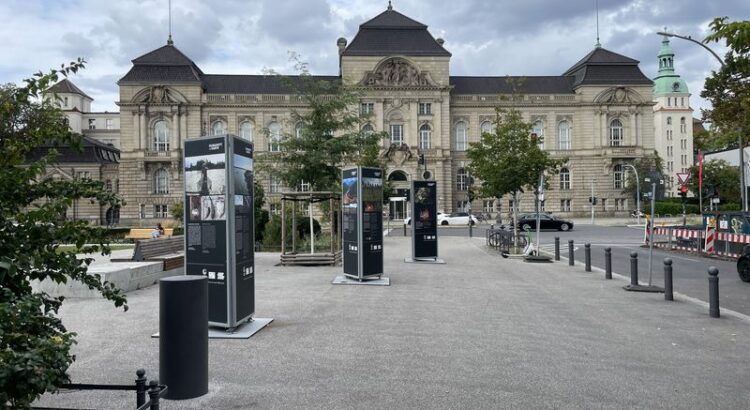 Blick entlang eines geplasterten Teils des Steinplatzes hin zum Hauptgebäude der UdK. Ein großer wilhelmischer Prachtbau. Wild bewölkter Himmel.
