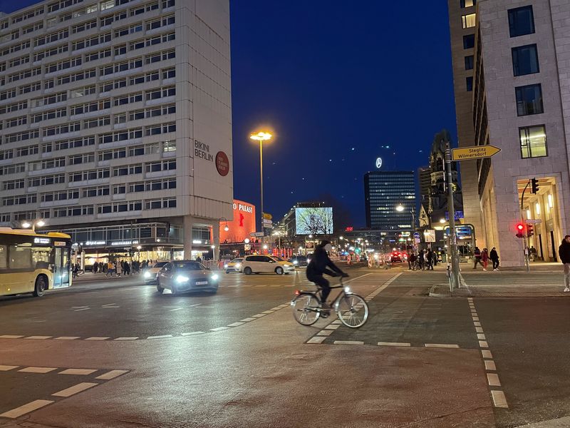 Nächtlicher Blick von der Kreuzung am Bahnhof Zoo Richtung Ku'damm. Eine Radfahrerin im Vordergrund, Autos, Teile des Bikinis Hauses und des Zoo-Palastes. Im Hintergrund Europa-Center und Kaiser-Wilhelm-Gedächtnis-KIrche