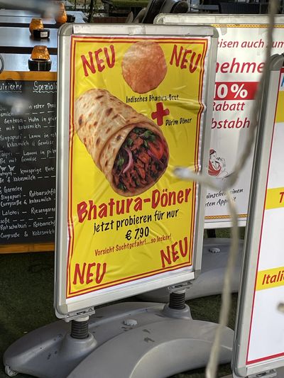 Schild, das den Bhatura-Döner anspreist. "Neu! Indisches Brot und Dürum Döner! Vorsicht Suchtgefahr" 